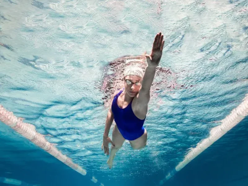 mulher-branca-com-maio-azul-e-touca-branca-em-nado-na-piscina